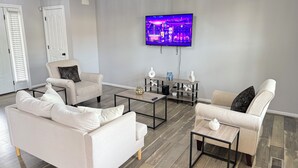 A modern living room with a flat-screen TV mounted on the wall, two sofas, a coffee table, and a side table with decorative items.