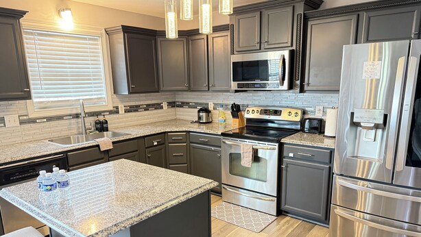 A modern kitchen with dark cabinets, stainless steel appliances, and a granite countertop.