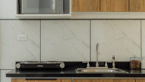 Een keuken met een magnetron, een kookplaat, een spoelbak en houten kastjes.