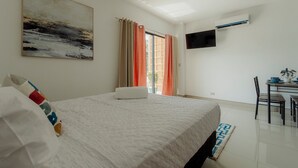 Een hotelkamer met een bed, een schilderij, een televisie en een zithoek met een tafel en stoelen.