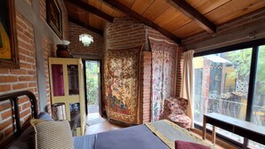 Une pièce confortable avec un lit, un plafond en bois, une fenêtre donnant sur un beau paysage et une porte menant à l’extérieur.