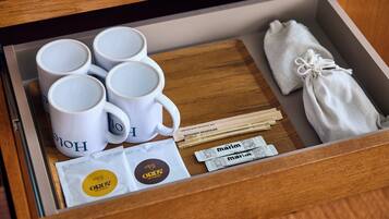 A drawer containing white mugs, a white cloth, wooden utensils, and two packets of marzipan.