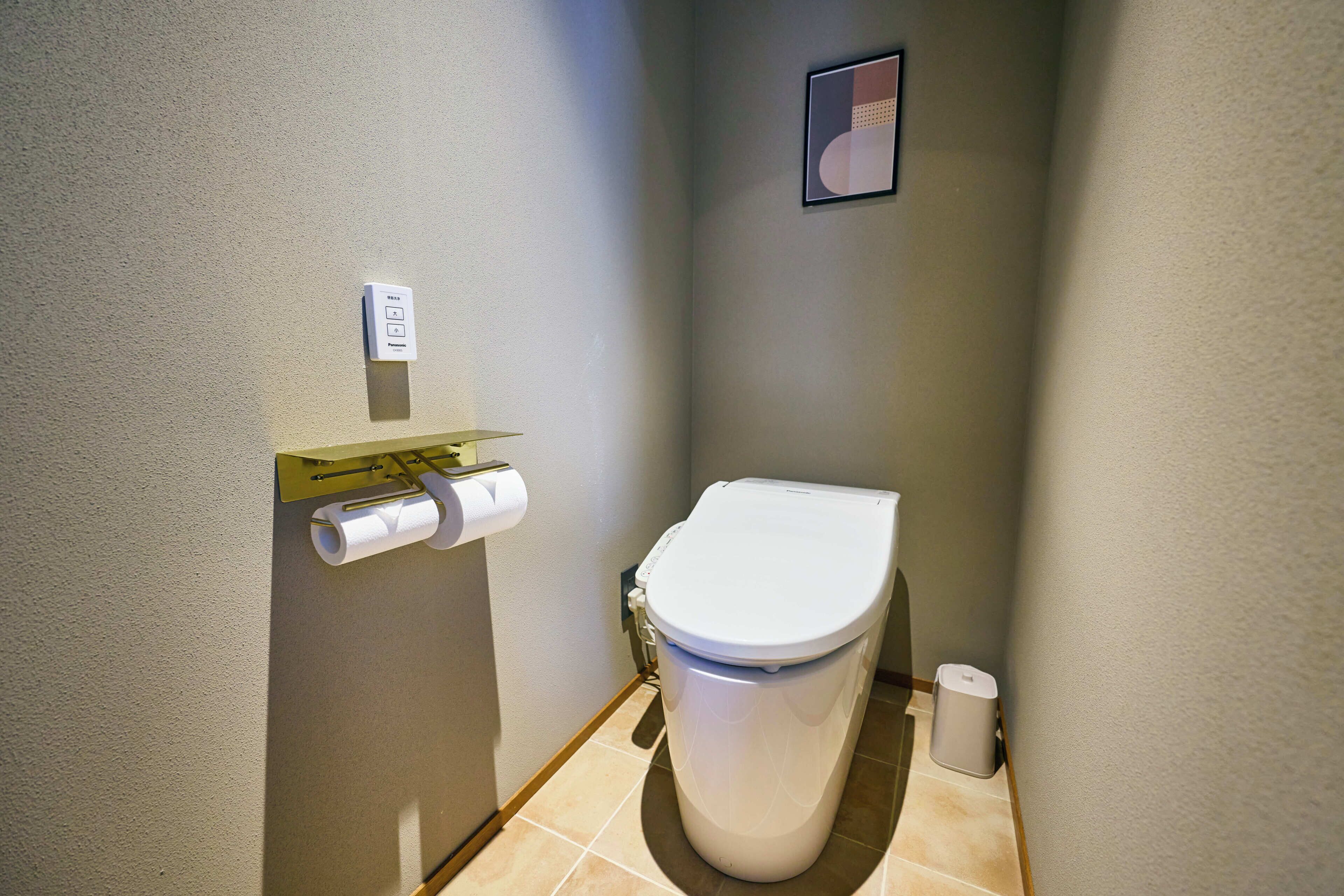 A small, modern bathroom with a toilet, a toilet paper holder, and a trash can.