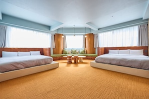 Habitación de hotel con dos camas, zona de estar y ventanas amplias.