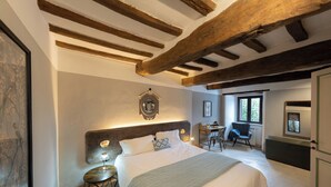 A bedroom with a large bed, a small round table, a chair, a desk, and a wardrobe.
