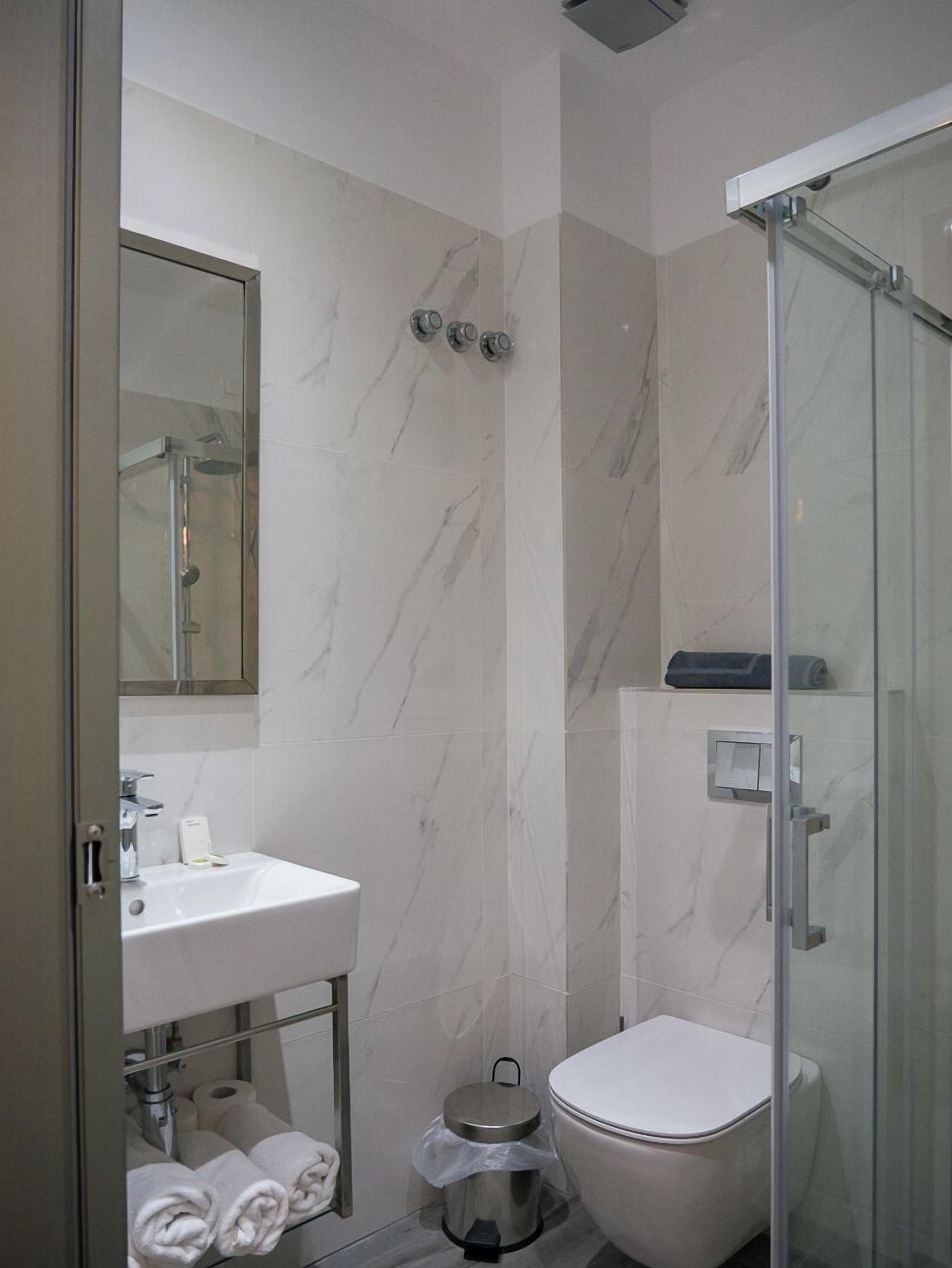 A modern bathroom with a glass shower enclosure, a white sink, and a toilet.