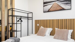 A hotel room with a bed, a wooden headboard, a wall-mounted shelf, and a painting of a dock. - #304 Albufeira Beach House by Home Holidays (Albufeira)
