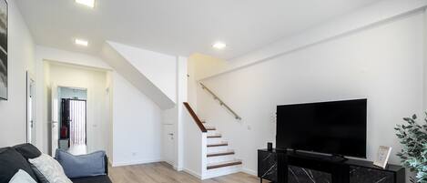 En moderne stue med trappe, et fladskærms-tv og minimalistisk indretning.