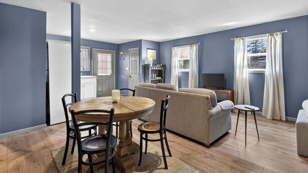 A living room with a dining table, chairs, a sofa, and a television.