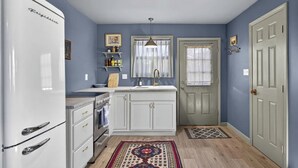 A compact kitchen with white cabinetry, a vintage refrigerator, and a