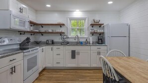 A modern kitchen with white cabinets, a wooden countertop, and a built-in microwave. - 3-bedroom Cozy Home in Ellsworth with AC, WiFi (Ellsworth)