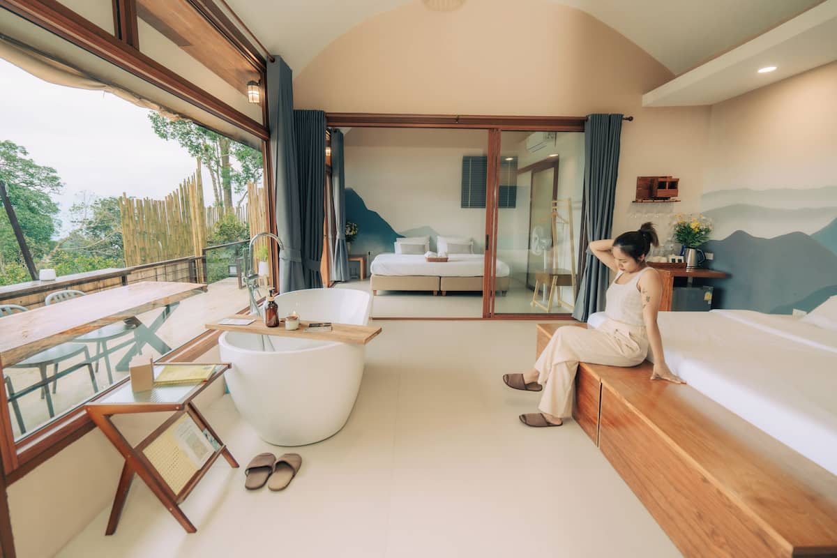A modern room with a large bed, a bathtub, and a dining area with a table and chairs.