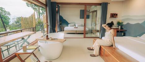 A modern room with a large bed, a bathtub, and a dining area with a table and chairs.
