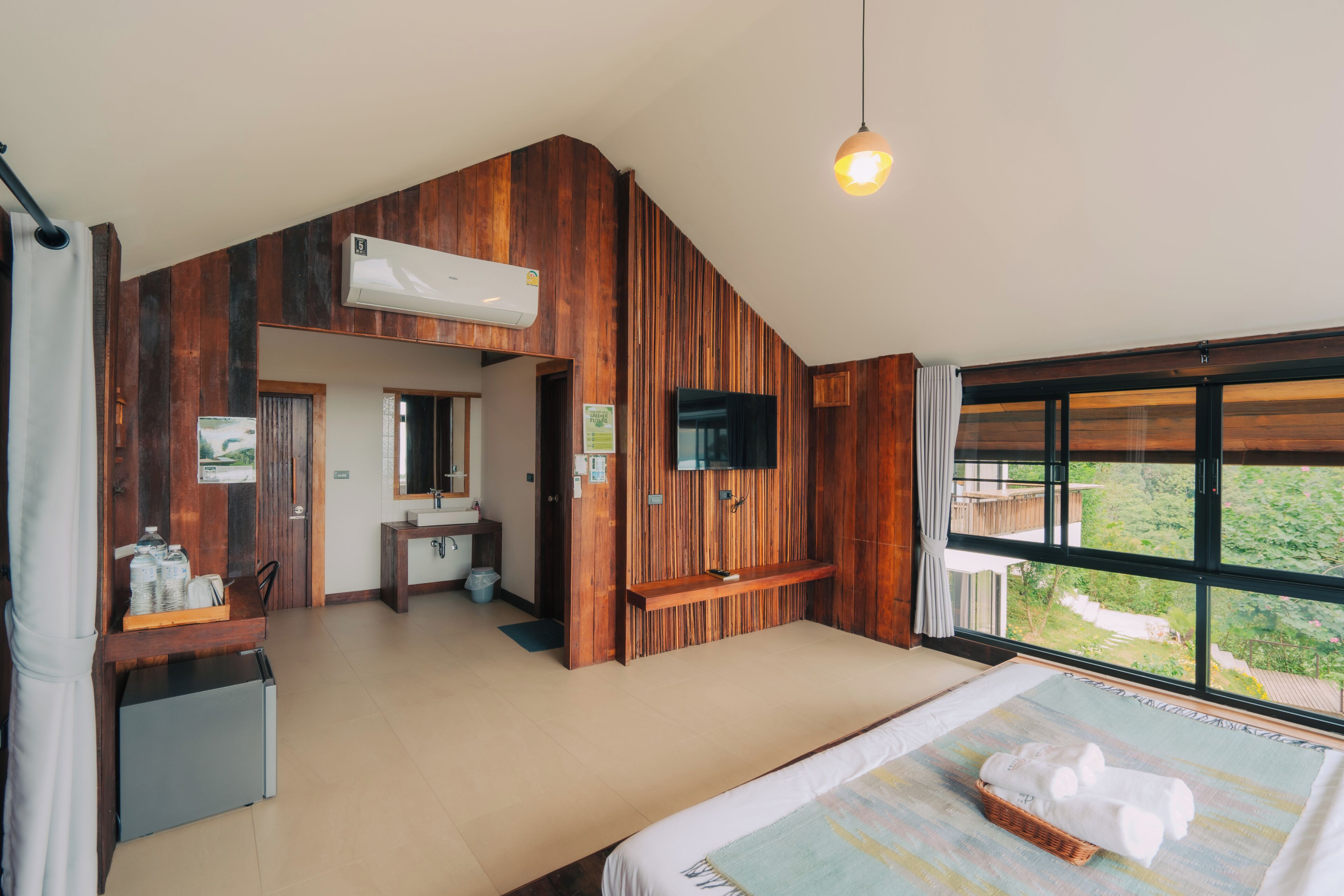 Un dormitorio con cama, un escritorio pequeño, televisor y ventana con vista.