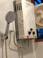 Un soffione con un tubo flessibile, un pannello di controllo con diversi pulsanti e una bocchetta di aerazione.