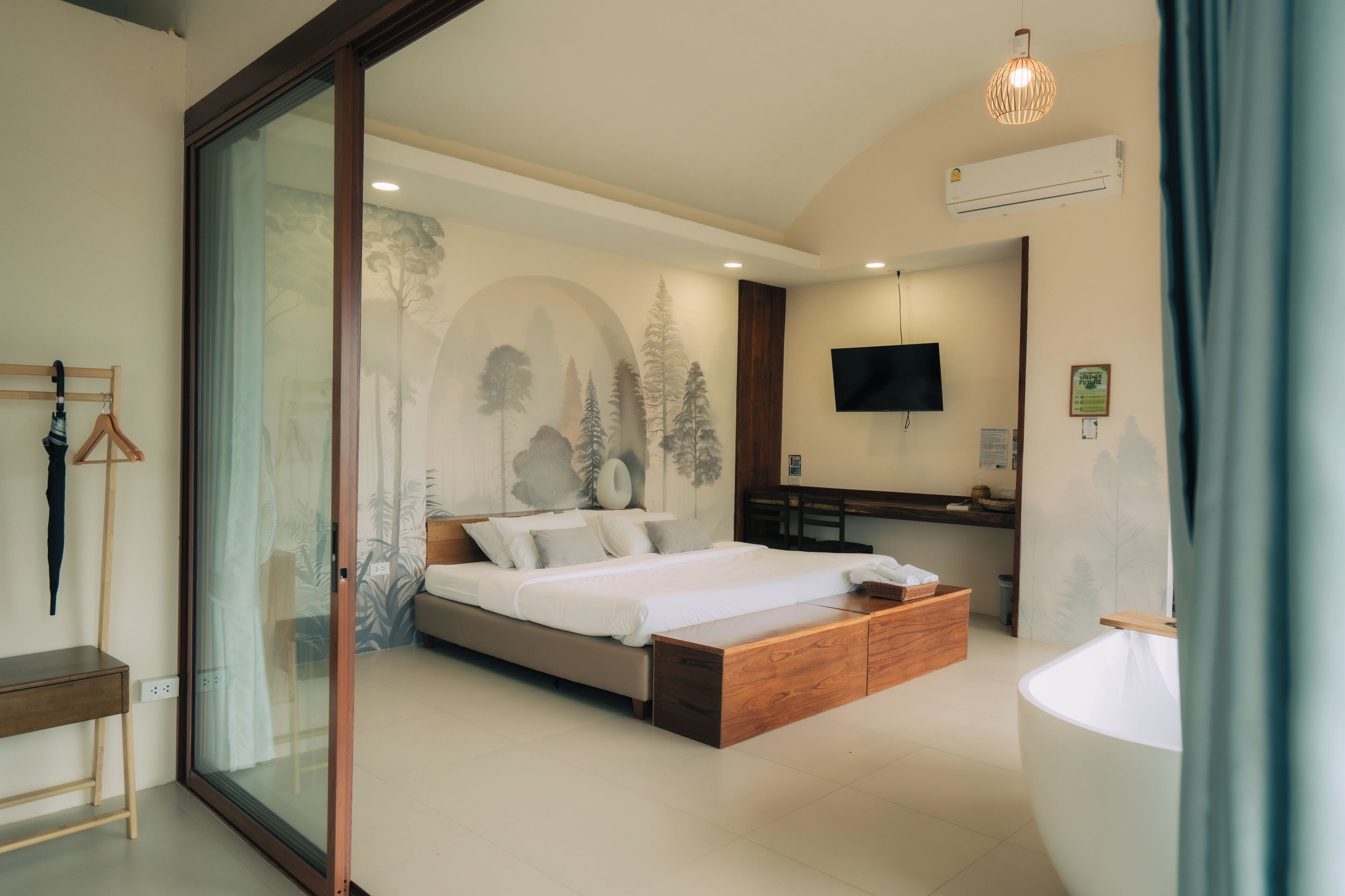 A modern bedroom with a bed, a desk, a TV, and a large window.
