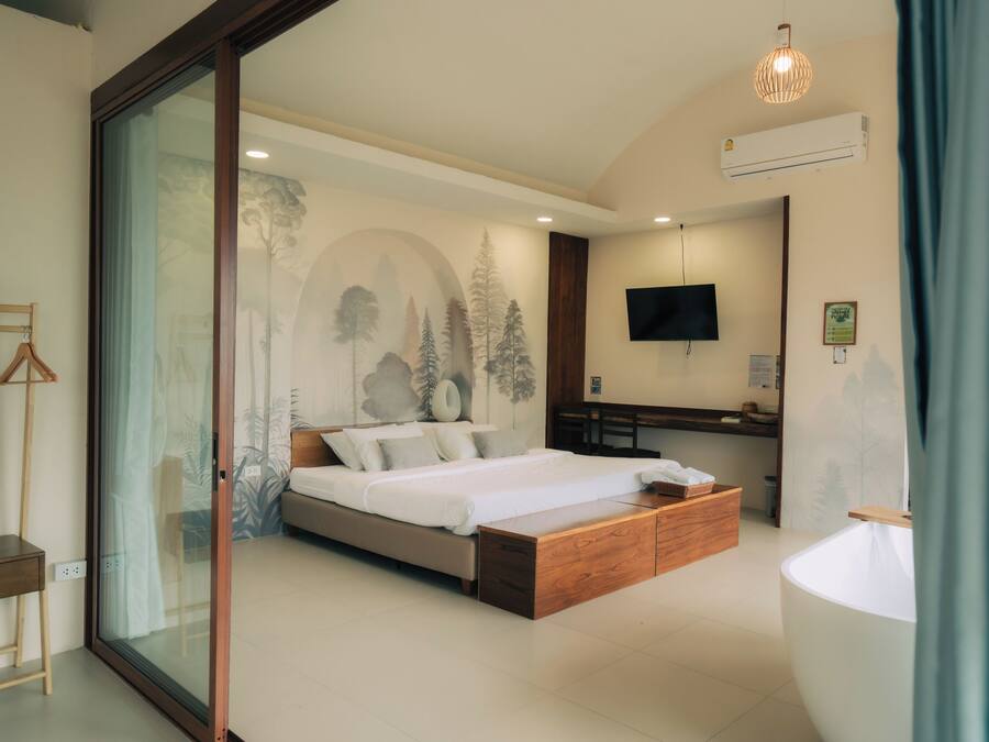 A modern bedroom with a bed, a desk, a TV, and a large window.