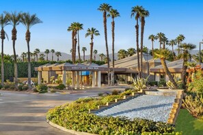 Stunning desert landscape surrounds the resort, featuring palm trees and a serene water feature.