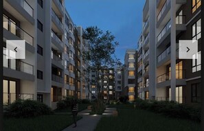 Stunning building with a symmetrical facade, featuring multiple floors with balconies and a beautifully maintained garden.