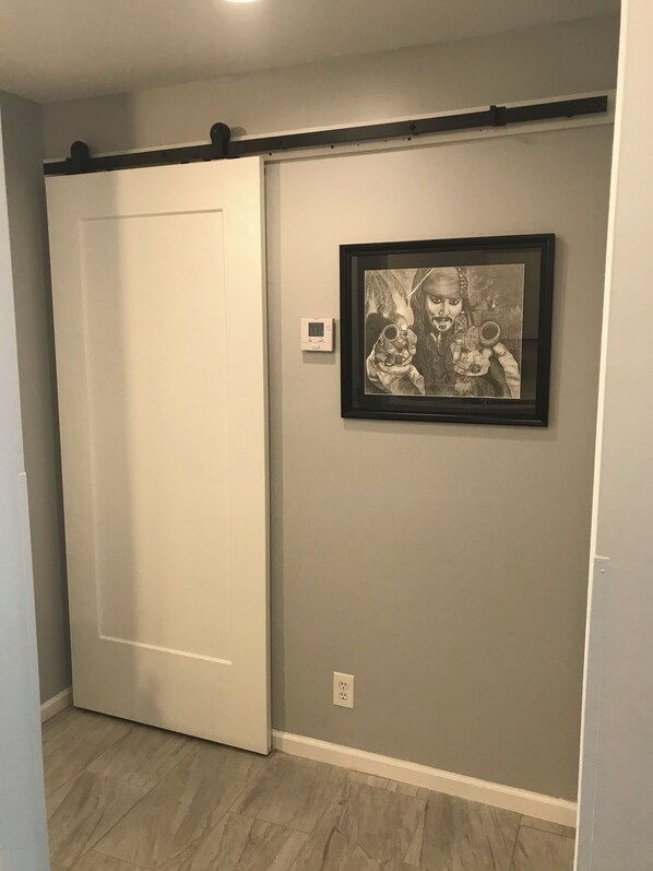 A room with a sliding door, a framed artwork on the wall, and a thermostat. - Bohemian Breeze - Shipyard Truman Annex condo in the heart of Old Town Key West (Key West)