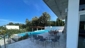 Ein Poolbereich auf dem Dach mit einem klaren, blauen Pool, einer Pergola und Sitzgelegenheiten im Freien.