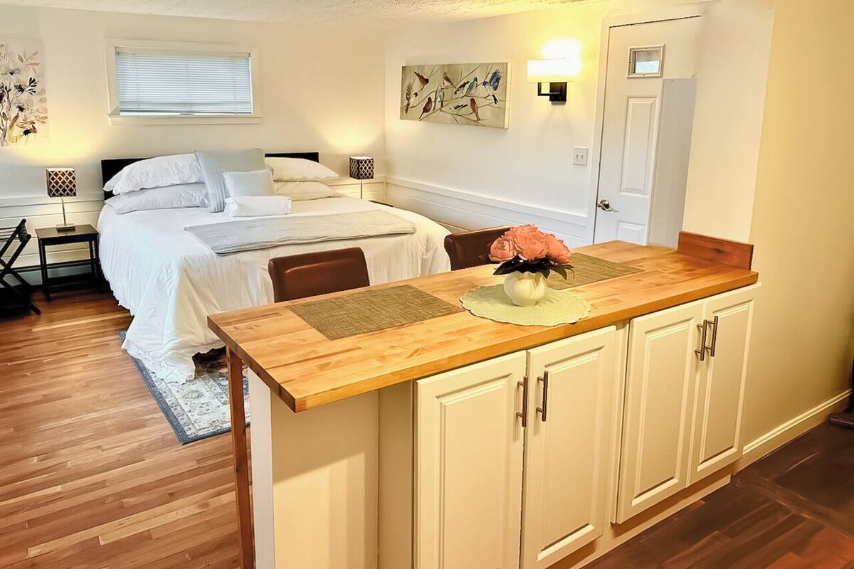 A bedroom with a bed, bedside table, lamp, and a painting on the wall.