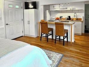 A bedroom with a bed, a small kitchenette, and a bathroom. - Lincoln Inn & Gallery (Woodstock)