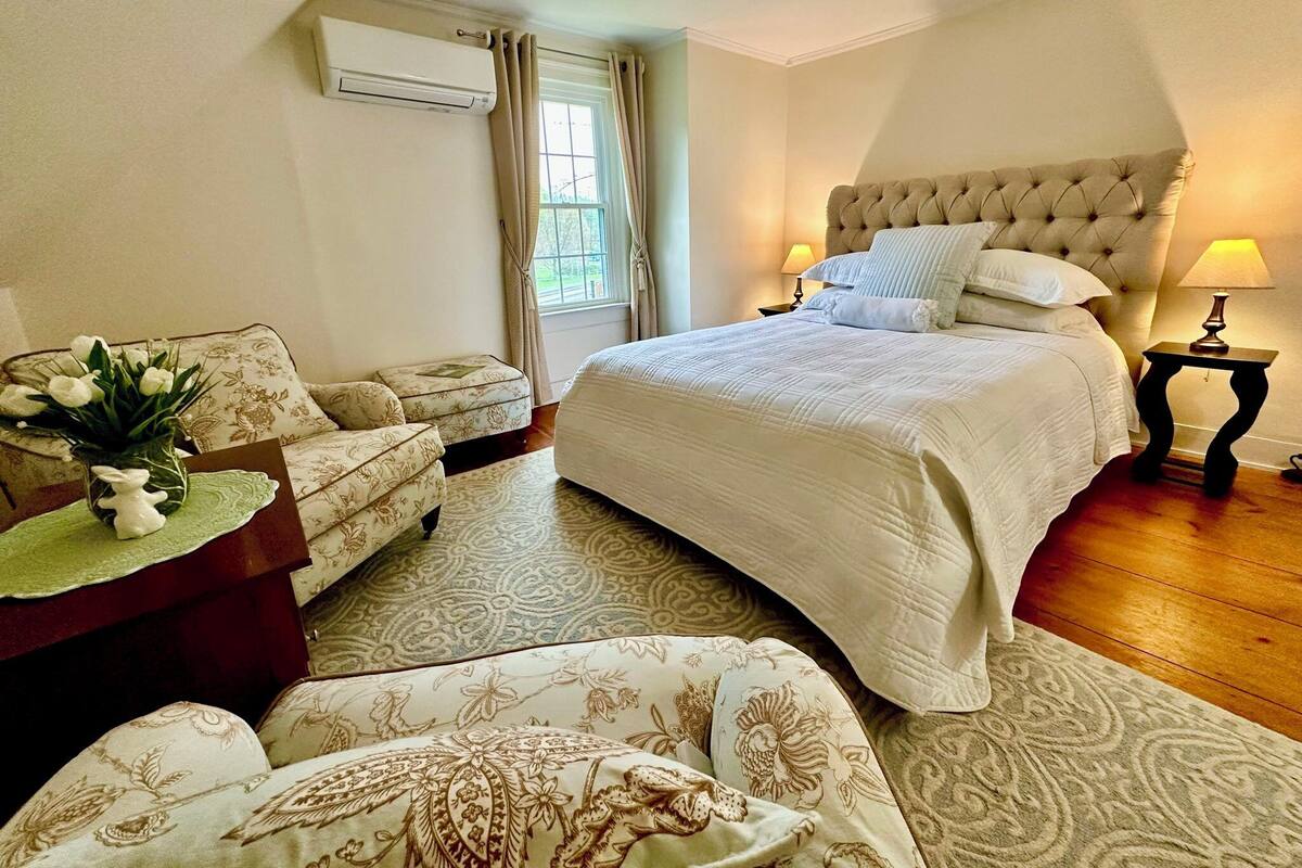 A bedroom with a bed, two bedside tables, a nightstand, a sofa, and a chair.