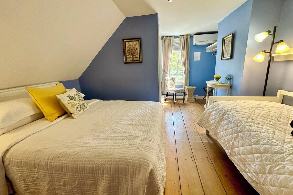 A bedroom with two beds, a small desk, and a chair.