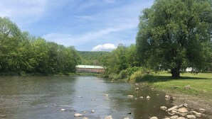 Ein Fluss mit Steinen, einer Brücke und Bäumen.