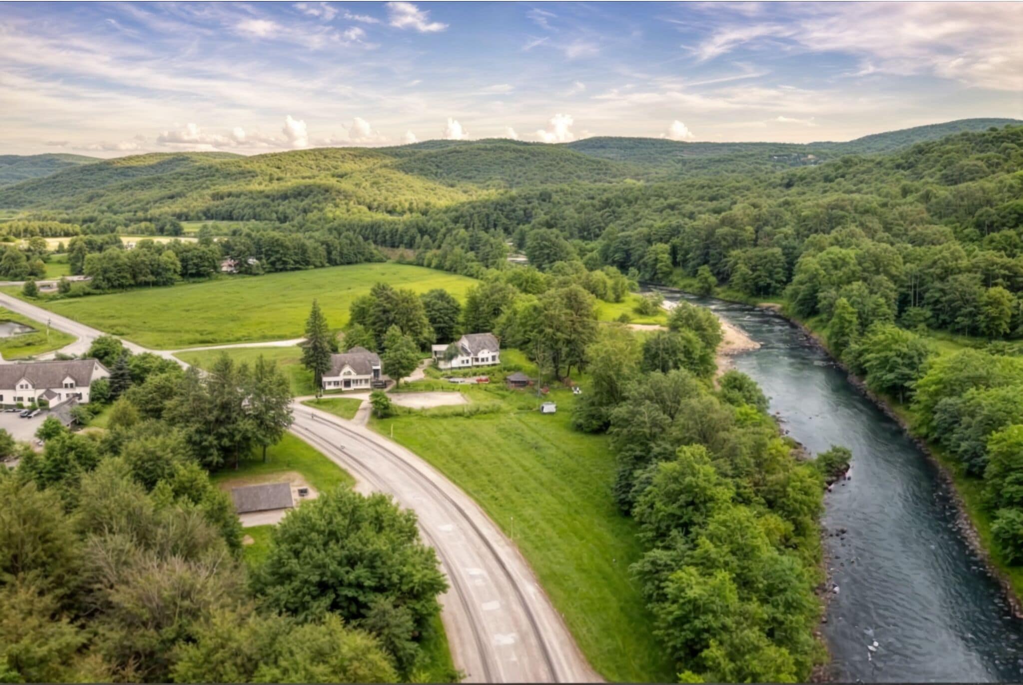 A rural landscape with a winding road, houses, and a river.