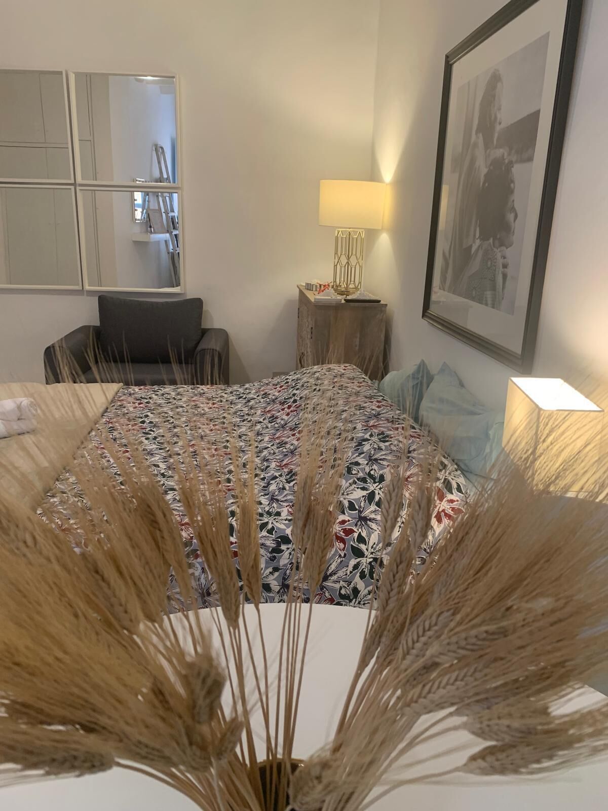 Une chambre d’hôtel avec un lit, un bureau, une chaise, une lampe et un tableau encadré au mur.