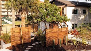Un jardí residencial amb tanca de fusta, pedres per caminar i diferents plantes.