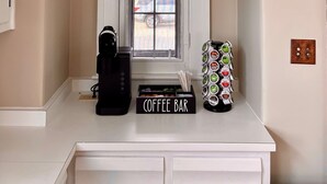 A coffee bar area with a coffee machine, a coffee station with various coffee pods, and a sign that reads "Coffee Bar".