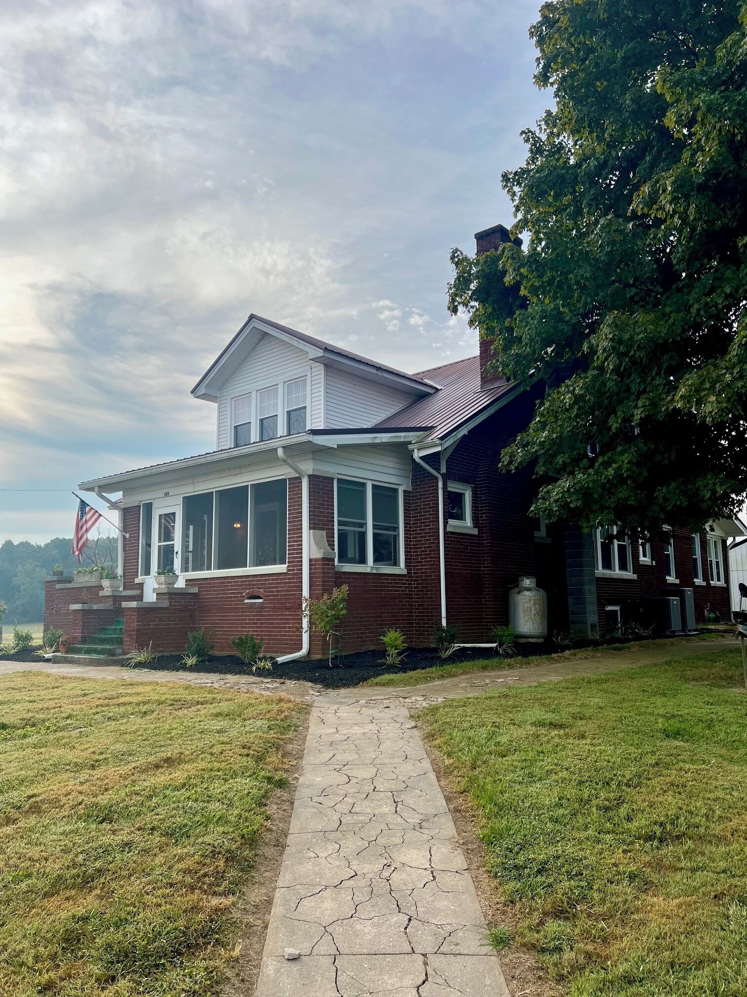 A two-story house with a brick facade, a front porch, and a pathway leading to the entrance.