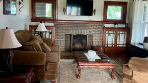 Una sala de estar con chimenea, televisor y una mesa de centro.