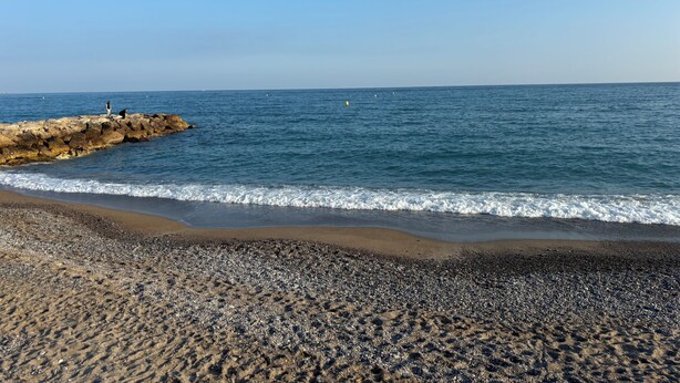 Una playa rocosa con olas rompiendo sobre la orilla.