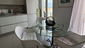 Una cocina moderna con armarios blancos, una mesa de comedor de vidrio y dos sillas blancas.