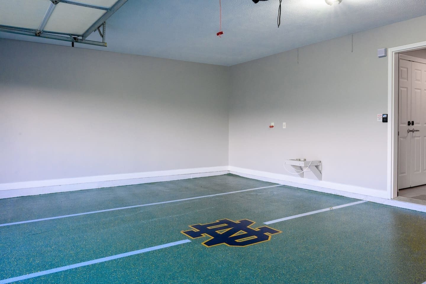 Una habitación con piso verde, paredes blancas y una puerta.