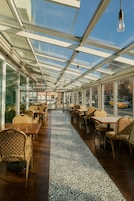 Ein Restaurant mit Glasdecke, Holztischen und -stühlen.