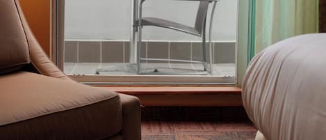 A hotel room with a balcony, a sofa, a chair, and a table.