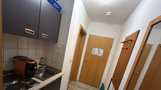 A compact kitchen with a stove, sink, and cabinets. - Alpenluxe Suite vacation apartment (Zwiesel)