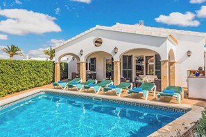 Un área junto a la piscina con sillas de descanso y una piscina.