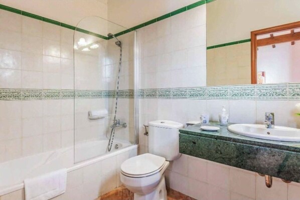 Un baño con ducha, inodoro y dos lavamanos.