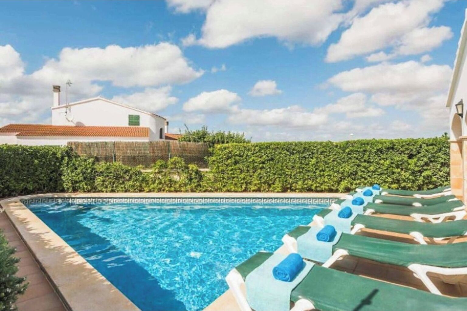Una piscina con sillas de descanso y un edificio al fondo.