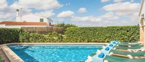 Una piscina con sillas de descanso y un edificio al fondo.
