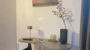 A small dining area with a table, two chairs, a vase with flowers, and a painting on the wall.