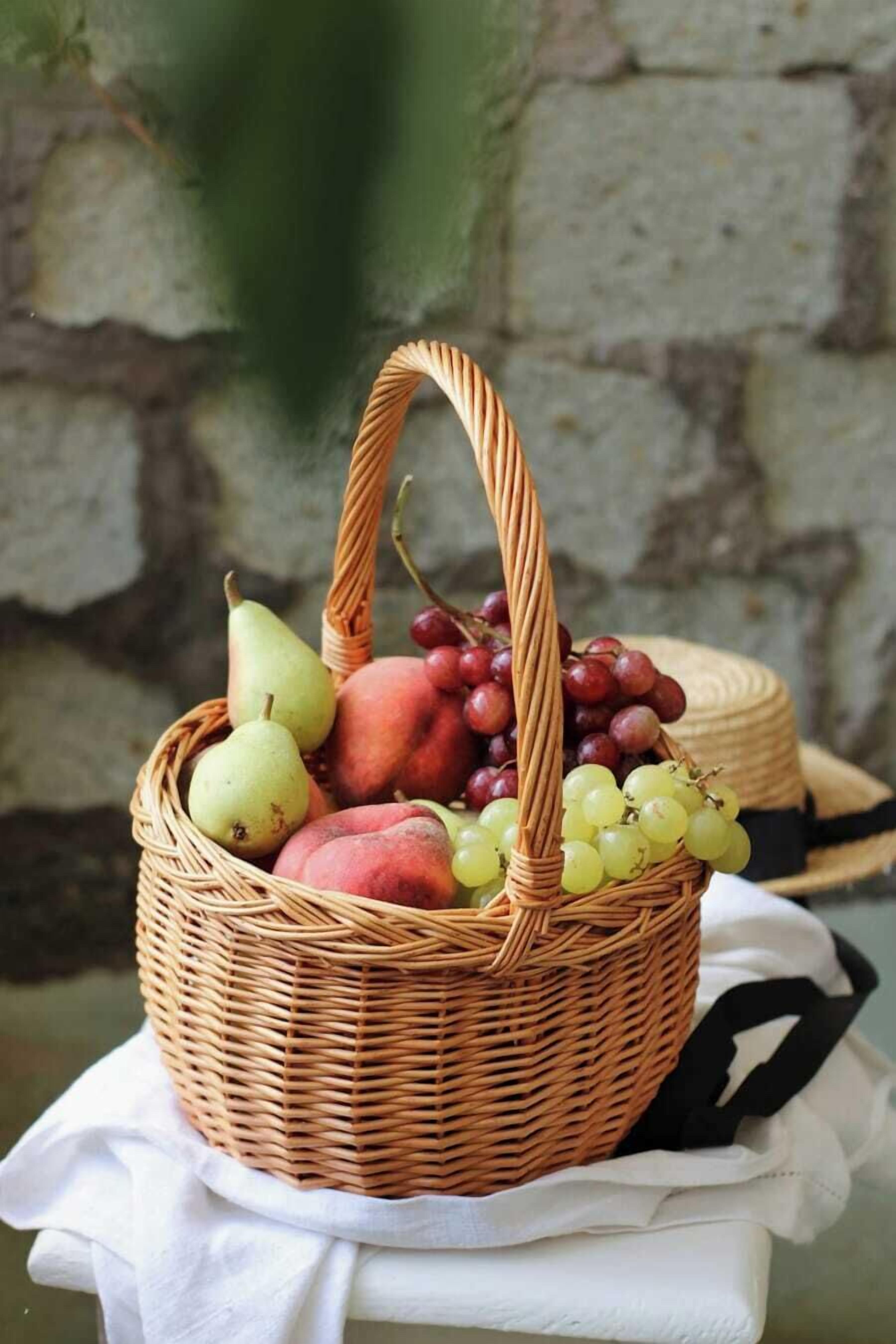 A wicker basket filled with fruits on a white cloth.