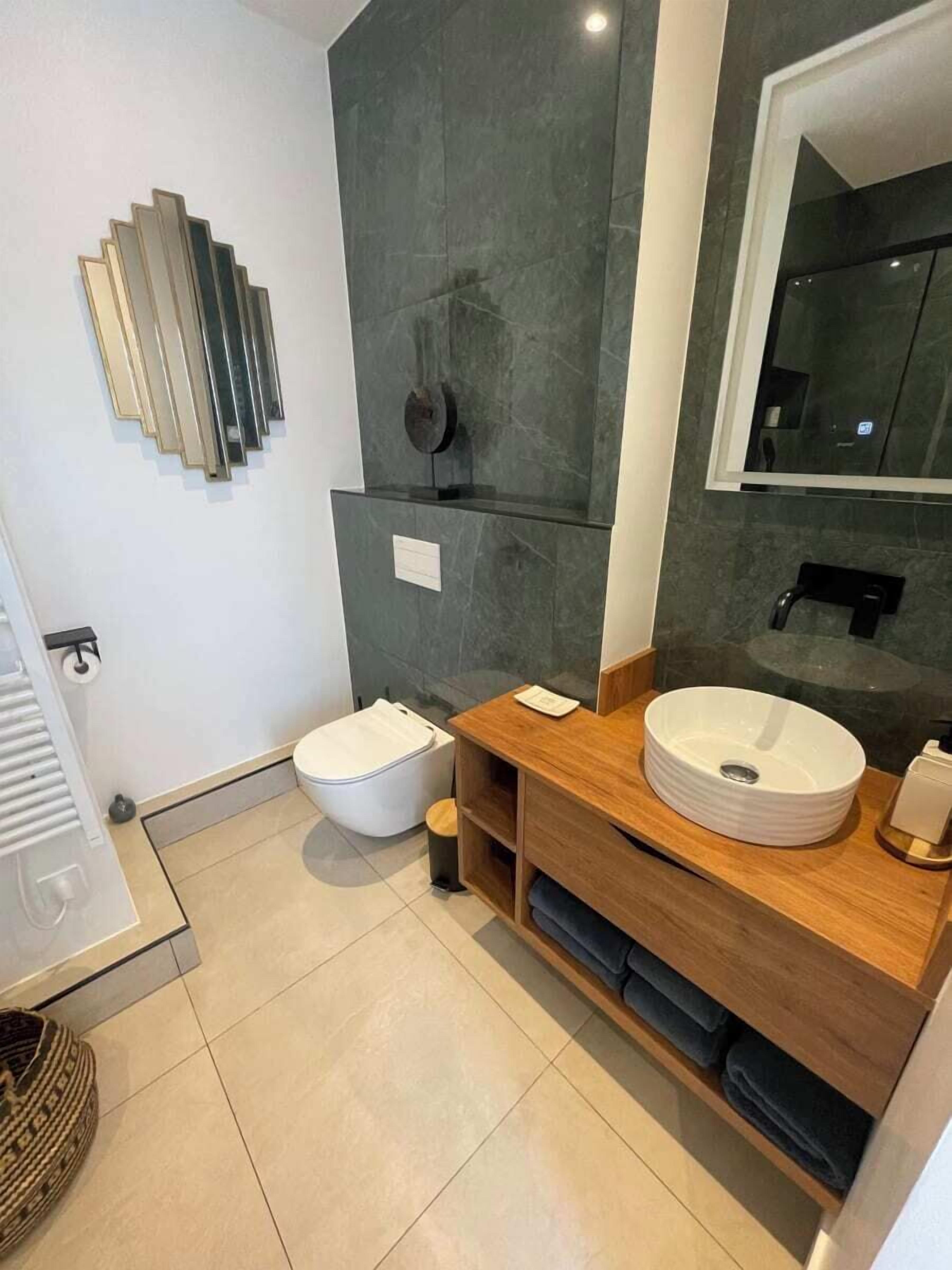 Un baño moderno con inodoro, lavamanos y espejo.