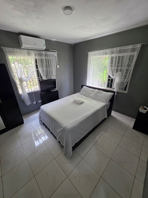 A bedroom with a bed, a bedside table, a wardrobe, and a window with curtains.